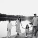 Monochrome photo of a family walking hand in hand along a serene lakeshore.