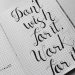 Close-up of motivational calligraphy on grid paper, inspiring message for productivity.